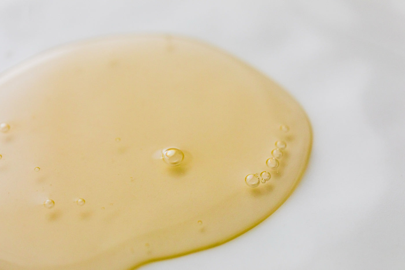 Goldenes Haaröl auf hellem Marmor